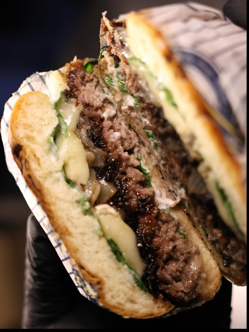 A cut burger with melted cheese and rocket